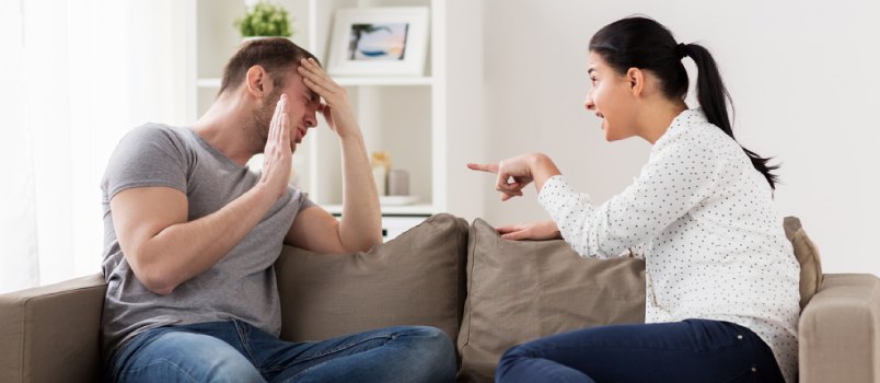 Man and woman arguing as they sit on the couch