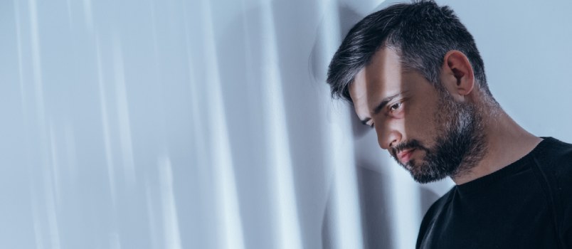 sad man leaning his head against the wall