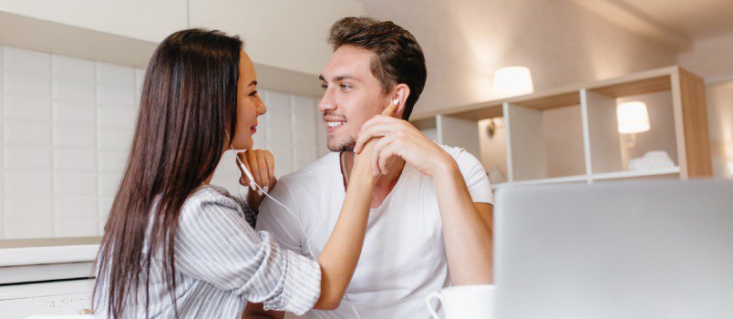Heterosexual couple sitting together as woman lovingly touches his face