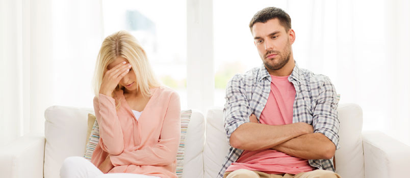 Sad Break Couple Seated Together On Couch At Home