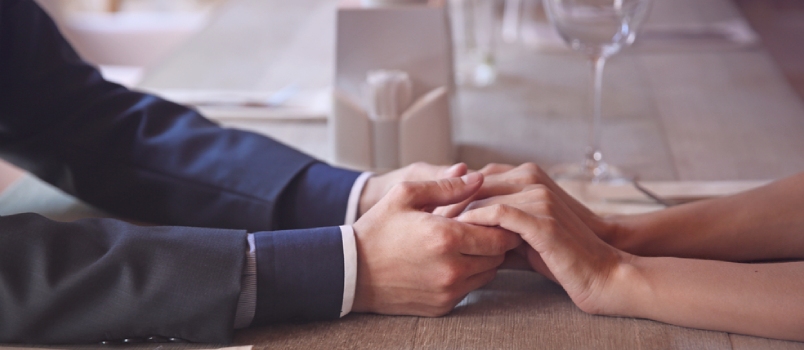 Man and woman holding hands at a restaurant table