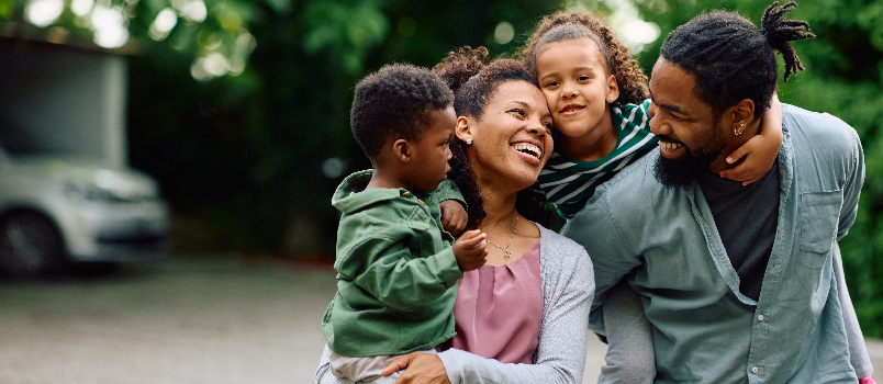 Happy Family Smiles Together Outdoors in the Suburbs 