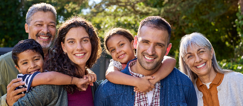 Happy Multi-Generational Family Smiling Together Outdoors in a Sunlit Garden