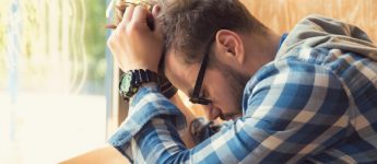 man sad and frustrated, sitting with his head in his hands
