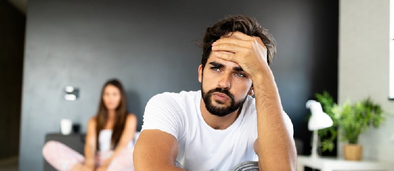 man sitting worried. while woman sits at the back
