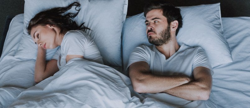 man lying awake at night in bed