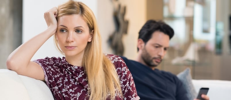 Sad separating couple sitting on the couch away from each other