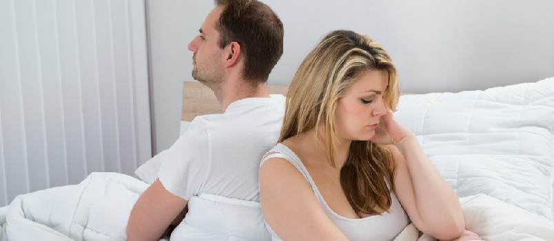 Unhappy Couple With Blanket Sitting On Bed