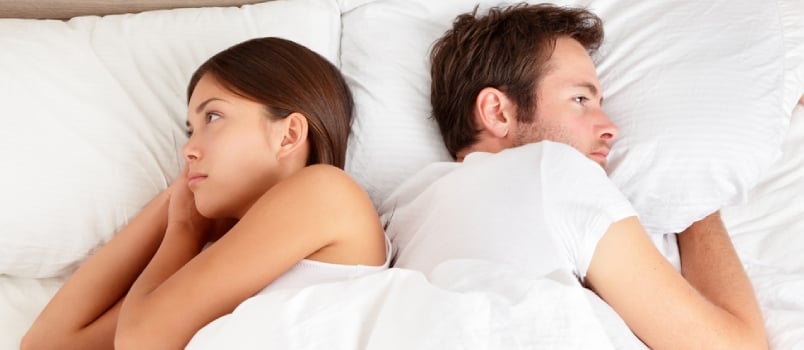 Man and woman facing opposite sides in bed after a fight