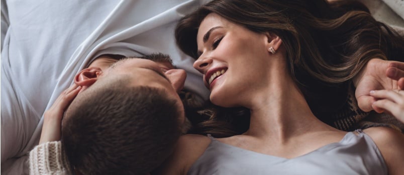 Young loving couple laying on bed looking at each other