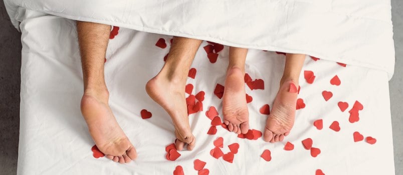 Couple legs cover with white bed sheet