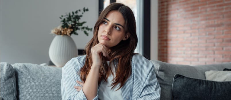 Woman sitting on couch thinking