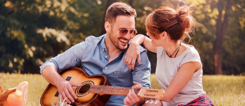 Man playing the guitar while woman looks at him and smiles