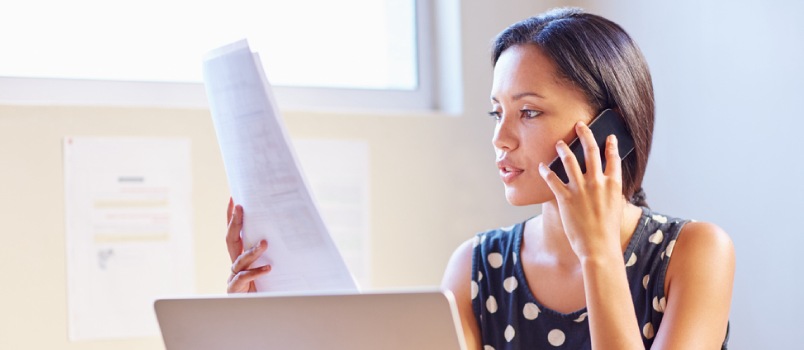 Woman looking at work papers while on a phone call