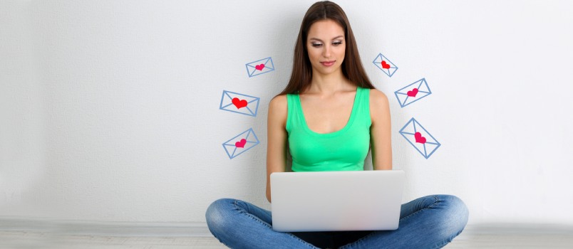 Woman sitting with laptop and many heart envelopes encircling her