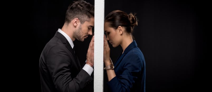 Side View of Sad Couple In Formal Wear Separated By Wall Isolated on Black