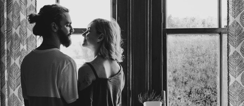 Happy Attractive Couple Standing Face To Face Together In Front of The Window At Home Kissing Concept