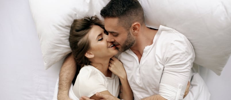 Young Beautiful and Loving Couple Kiss and Hug Into Bed