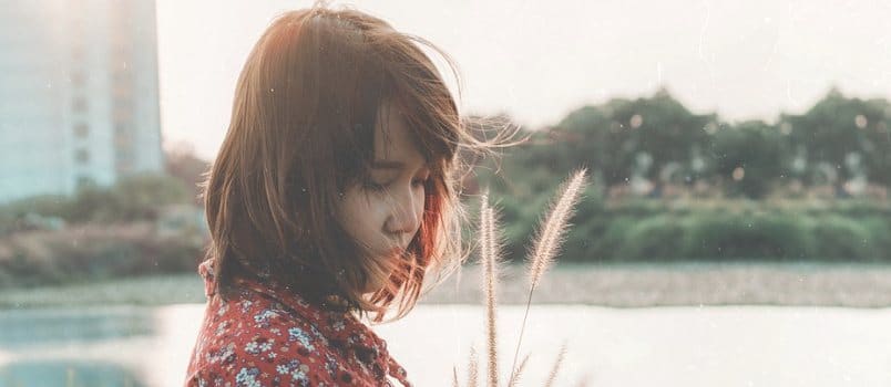 Sad woman standing outdoors thinking