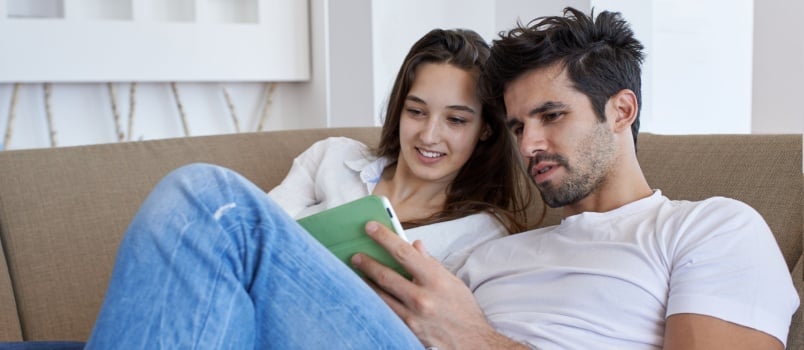 Couple watching something on the tablet while laying down on the couch