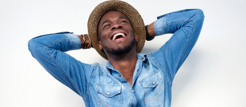 close up portrait of a young man laughing with hands behind head on white background