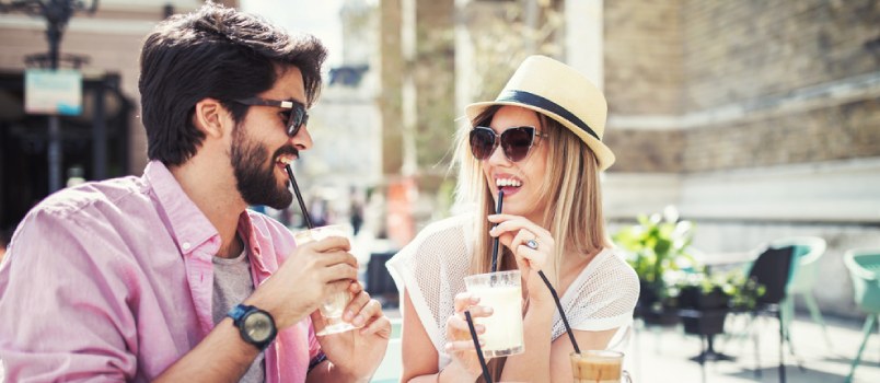 couple eating outdoors while sipping on their drinks