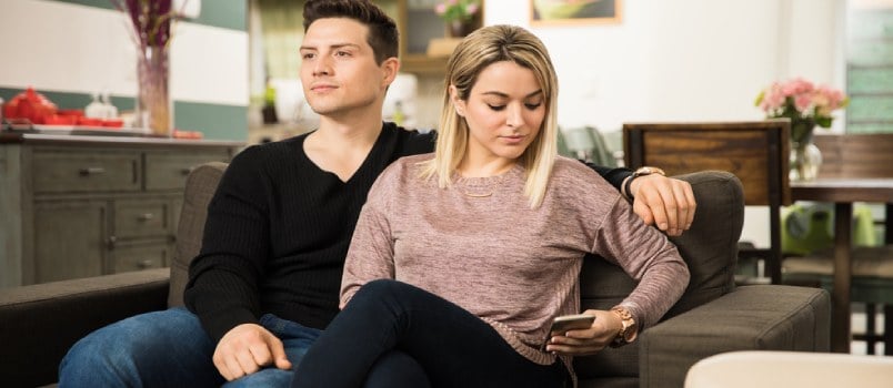 wife busy on phone sneakily and husband not noticing