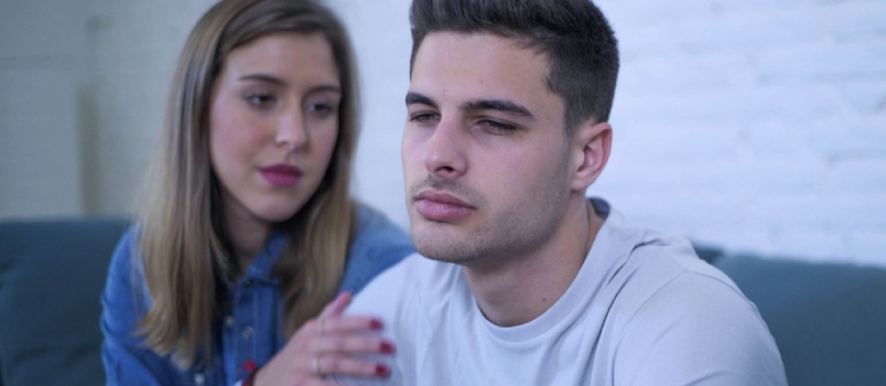 sad man is looking away while woman is trying to get his attention