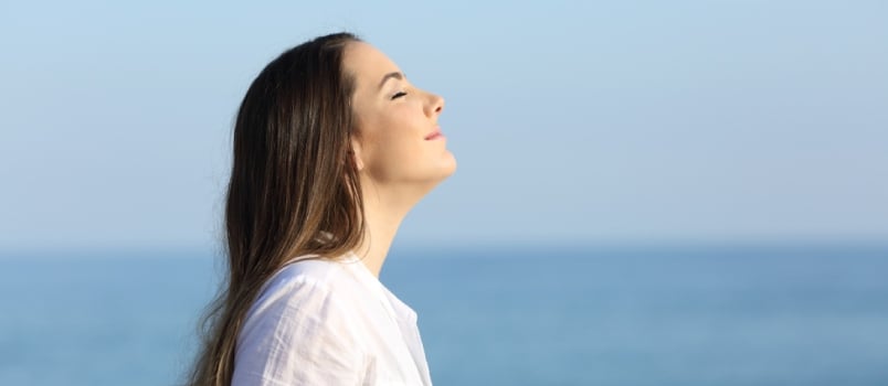 Smiling woman standing with eyes closed feeling hopeful