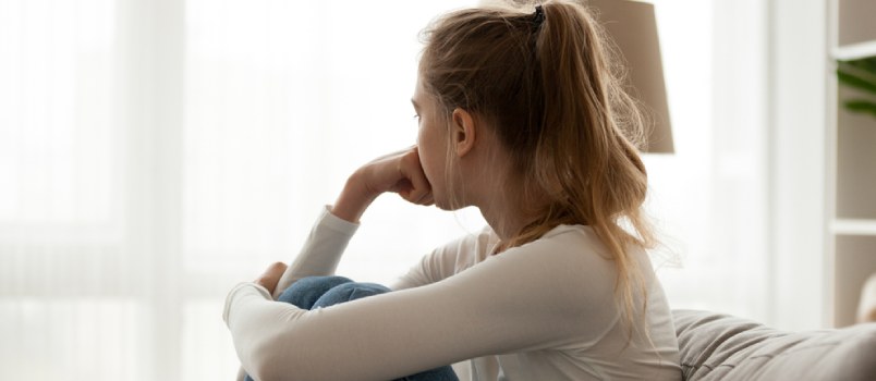 Sad woman sitting on couch thinking about breakup