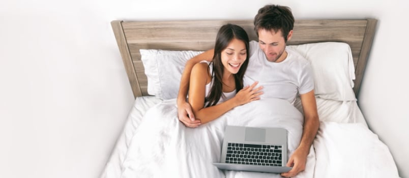 Couple using laptop on bed at bedroom