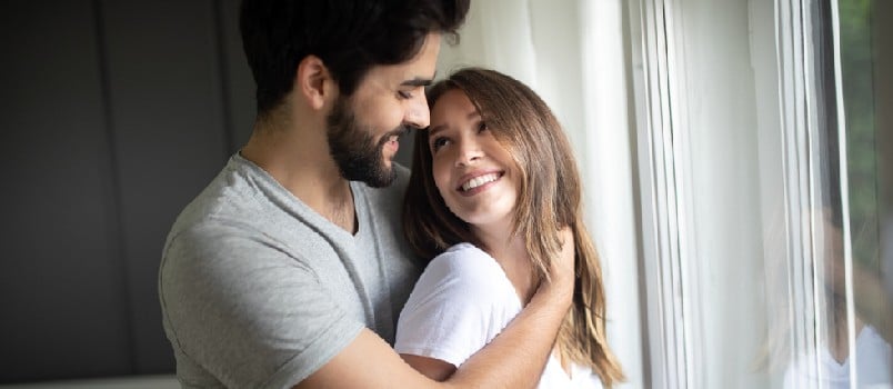 Beautiful happy couple of young lovers are hugging indoors at home, with love and tenderness