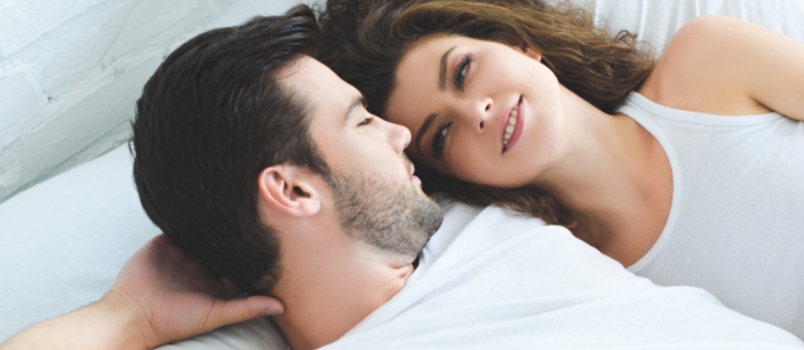 High Angle View of Beautiful Young Couple Lying in Bed and Smiling Each Other