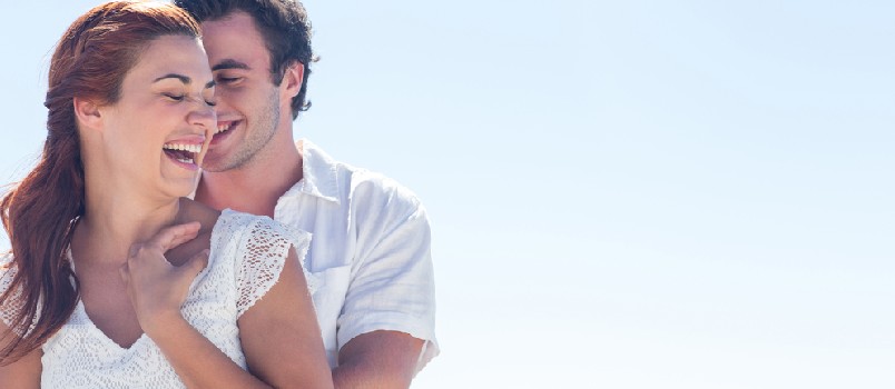 Happy couple hugging and laughing together at the beach