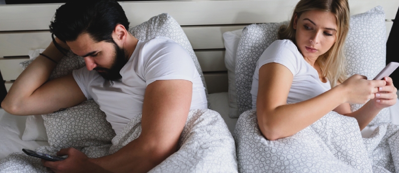 Man And Women Using Mobile Phone On Bed And Hiding Each Other Screen While Women Looking Cross Eyes