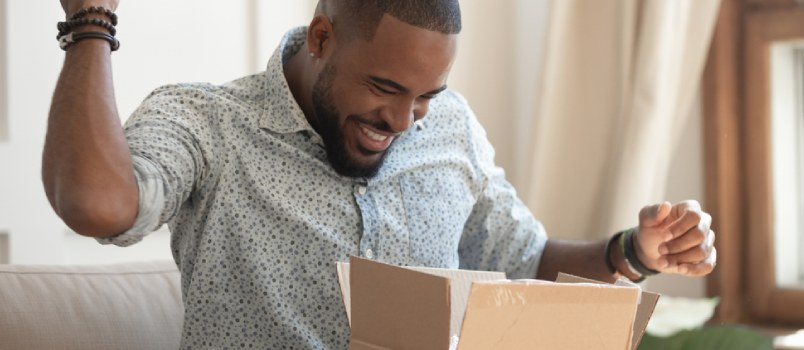 a happy black man holding a box