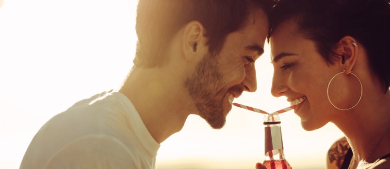 Man and woman romantically drinking from the same bottle