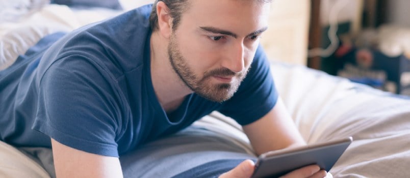 Man working on laptop laying on bed