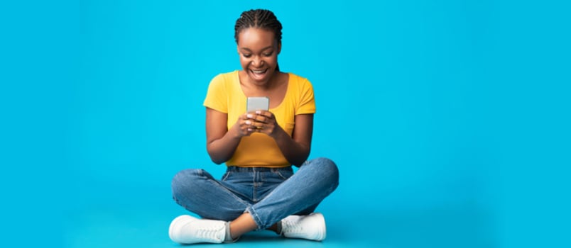 women texting over phone with blue studio background