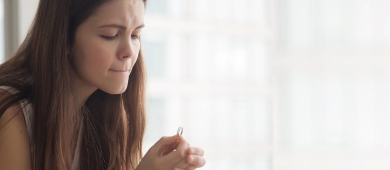 Upset Divorcee Lady Sad Sitting And Holding Her Wedding Ring Looking On It