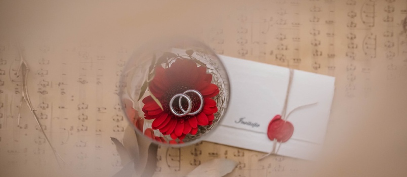 Keep the colors calm and not loud Pair Of Silver-colored Wedding Rings In A Glass Bowl with the invitation Card
