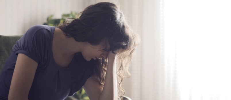 Depressed Young Woman Sitting in Chair at Home