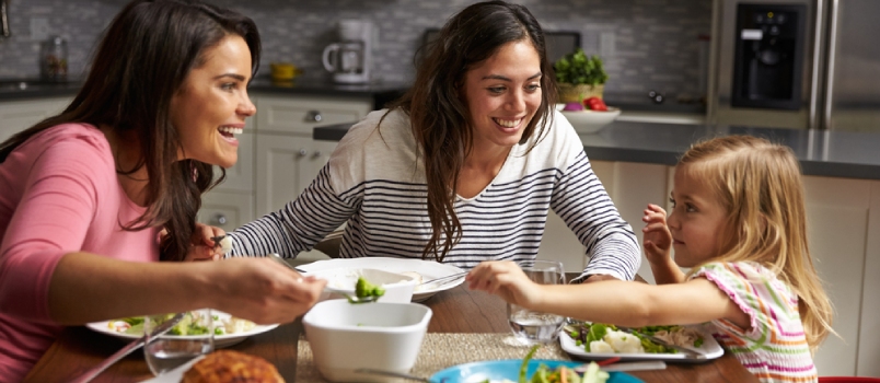 Female Gay Couple And Daughter Having Dinner In Their Kitchen