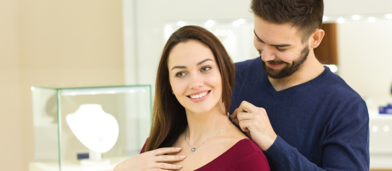 Man Helping His Girlfriend To Try On A Golden Necklace