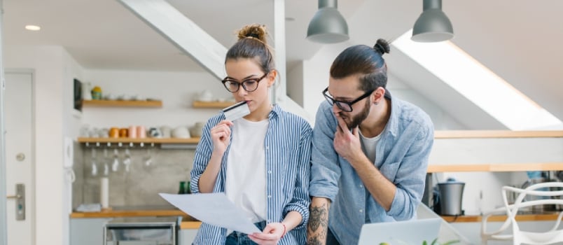 Young Beautiful Couple Thinking With The Bill Paper In Hand With A Credit Card