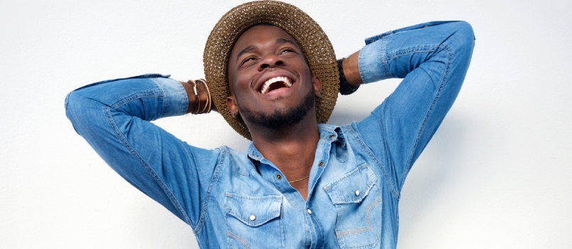 Close Up Portrait Of A Young Man Laughing With Hands Behind Head On White Background