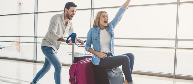 Romantic Couple In Airport With Suitcases Are Ready For Traveling Having Fun On Luggage Trolley