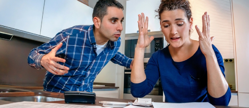 Angry Young Couple Shouting In A Hard Quarrel By Their Many Debts At Home. Financial Family Problems Concept