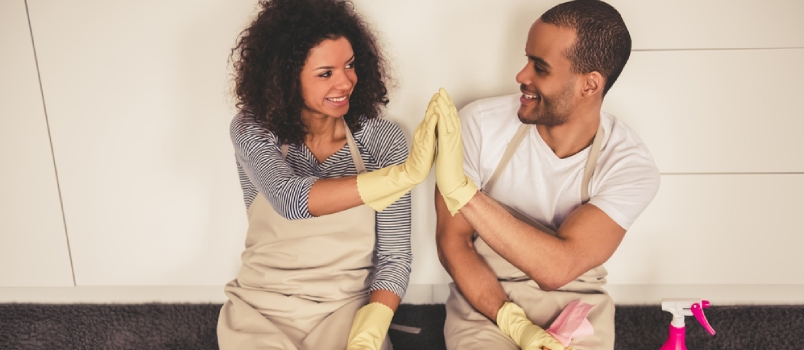 Beautiful Young Afro American Couple Is Giving High Five And Smiling While Sitting On The Floor In Kitchen After Cleaning It