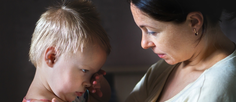 Mother Comforting Crying Son At Home Side View Of Adult Woman Touching And Soothing Upset Toddler Wiping Tears In Dark Room At Home